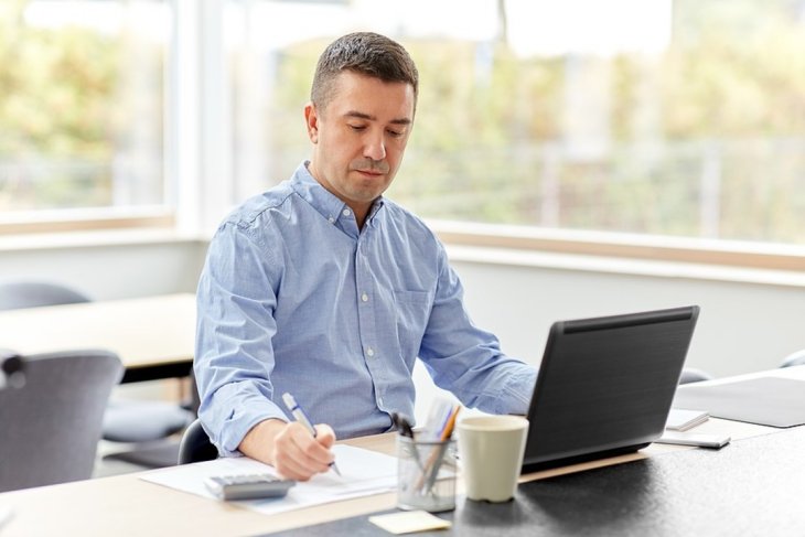 Man sitting at his desk writing on a document.