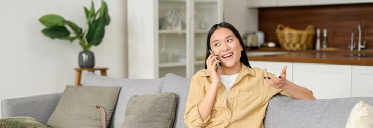 Portrait,of,smiling,young,woman,talking,by,smartphone,and,looks